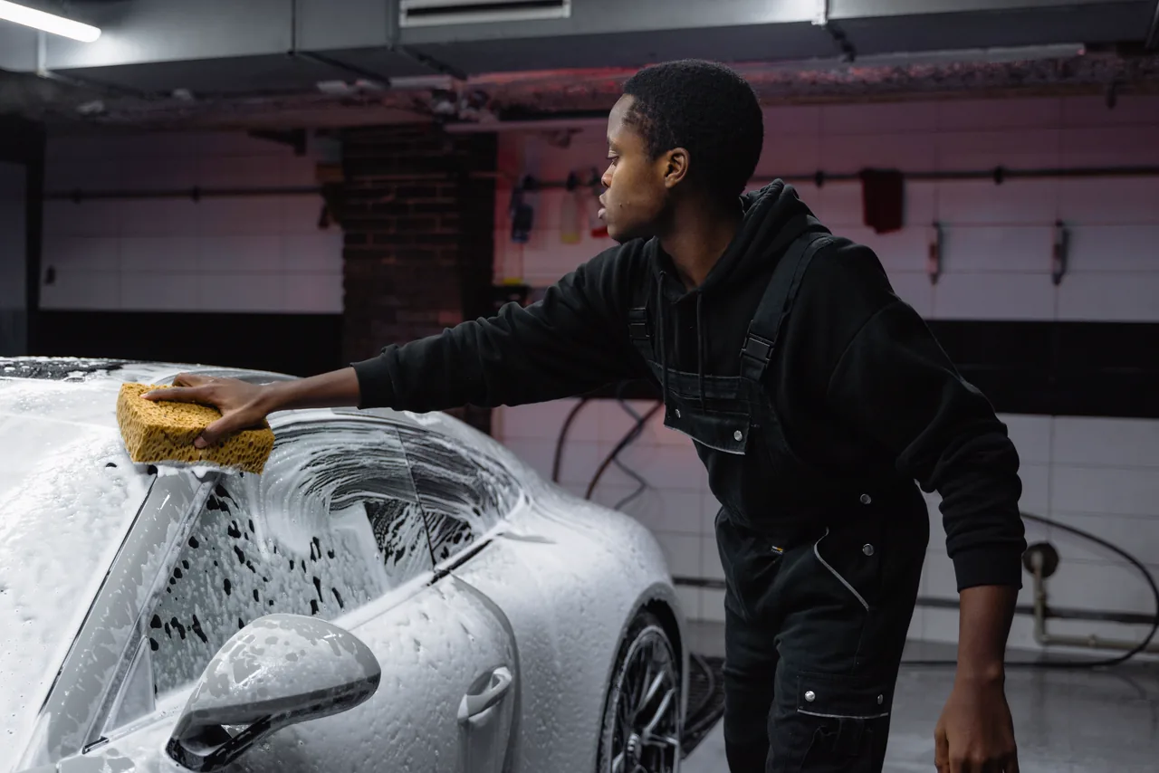 A car detailer washing a sports car